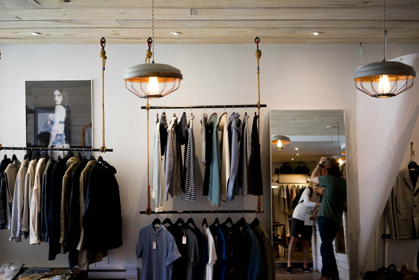 Warm, sunlit independent clothing boutique interior with a staff member helping a customer