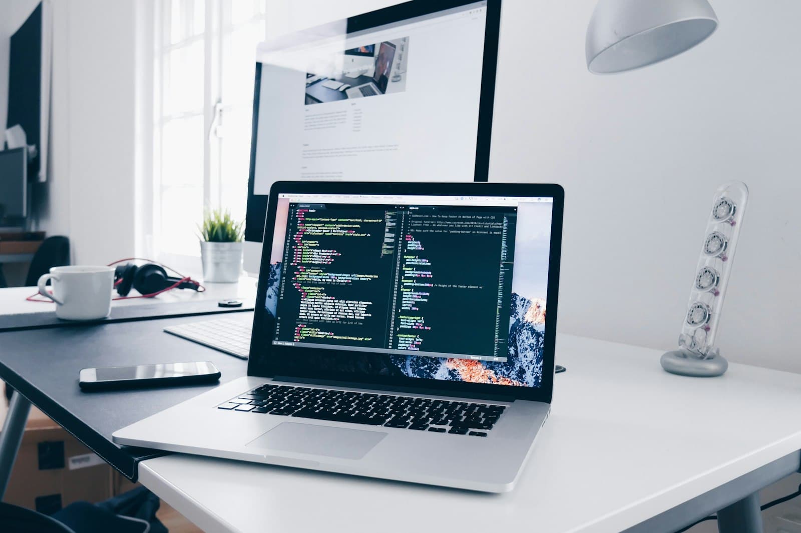 A laptop displaying lines of code on a bright, minimal white desk